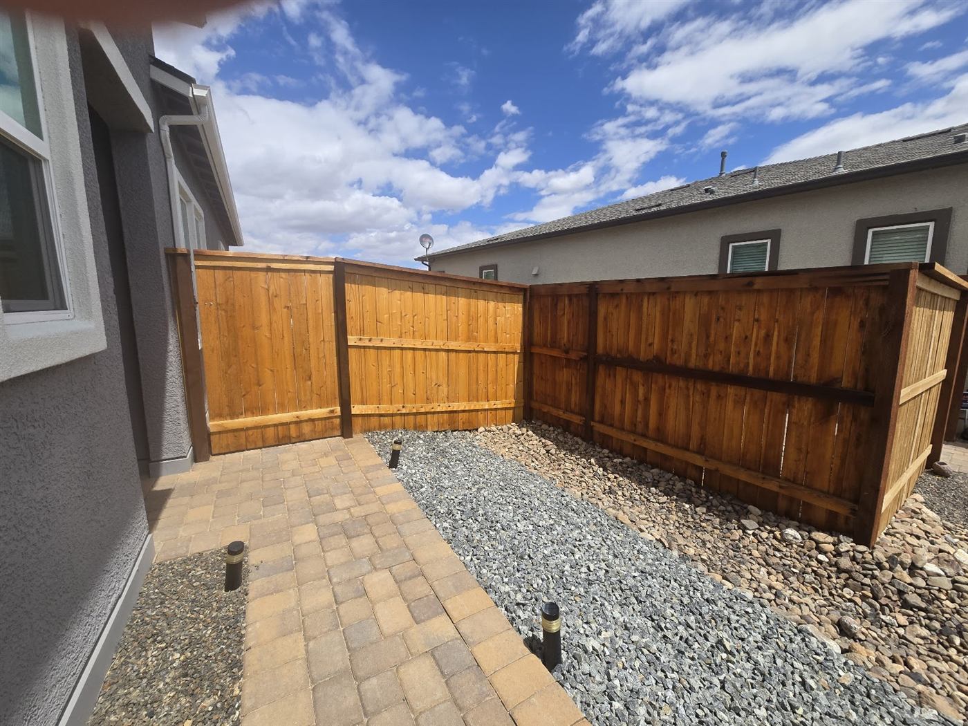 Stained wood fence in a backyard corner near a paver patio