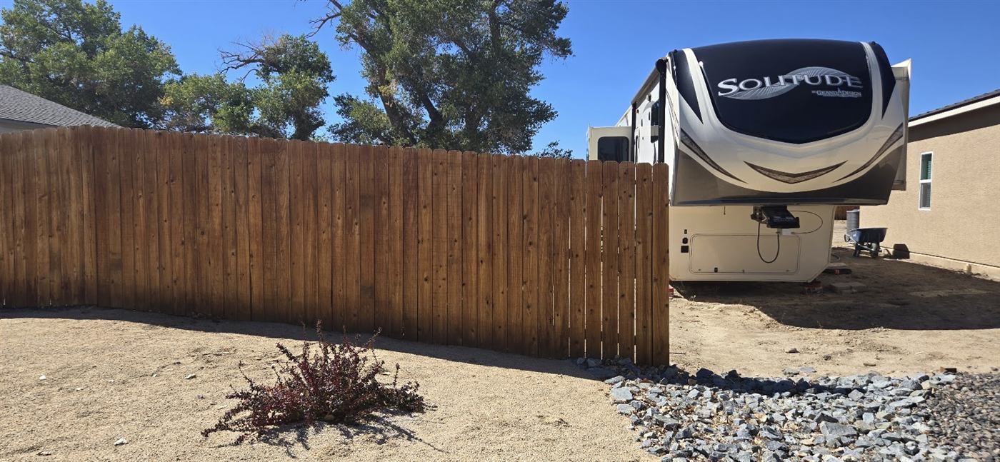 Newly stained wood fence along a side yard next to an RV
